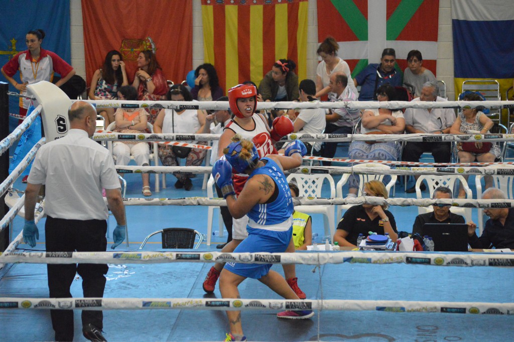 Sobre el cuadrilátero del Polideportivo de Novo Mesoiro dos competidoras gallegas, pujan deportivamente por la Plata y el Oro en la final del peso máximo femenino. Al fondo y de izquierda a derecha 